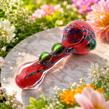 Red and green swirl glass spoon pipe displayed at an angle on a clean white background with decorative raised accents along the handle