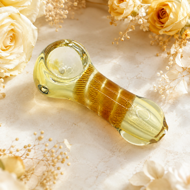 Amber and cream striped glass spoon hand pipe on a white background