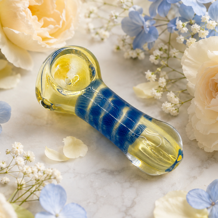 Blue striped glass spoon hand pipe displayed on a floral background