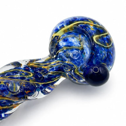 Close angled view focused on the spoon bowl opening and intricate blue-and-gold textured glass pattern