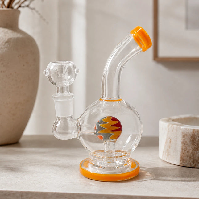 Yellow-accented 6-inch mini glass water pipe staged on a warm neutral tabletop with curved neck and round orb chamber