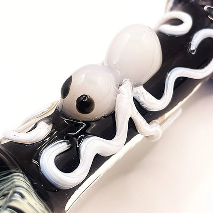 Macro detail of the white raised spider centerpiece on glossy black glass with soft marbled blue and gray accents