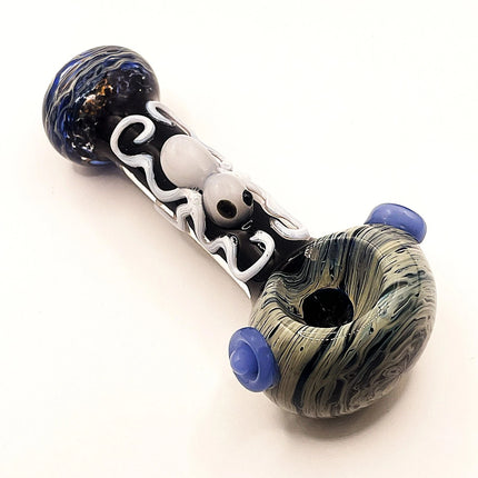Angled product view of the spoon hand pipe showing the black body, swirling white pattern, and marbled blue glass at both ends