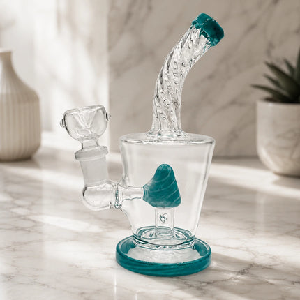Clear mini glass water pipe with teal cone percolator and teal-rimmed mouthpiece displayed on a soft neutral tabletop setting