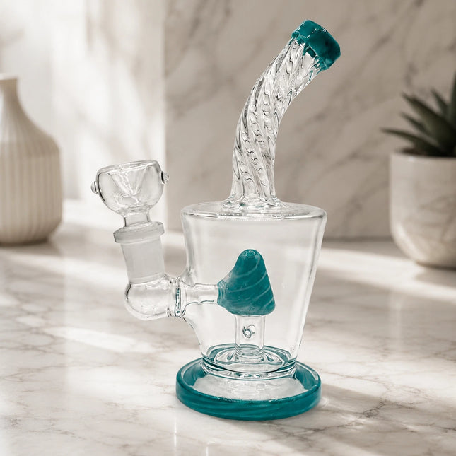 Clear mini glass water pipe with teal cone percolator and teal-rimmed mouthpiece displayed on a soft neutral tabletop setting