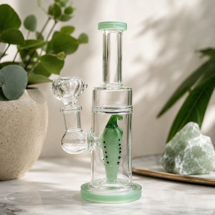 Mint green pepper glass bong displayed on a bright tabletop with leafy plants and soft natural window light