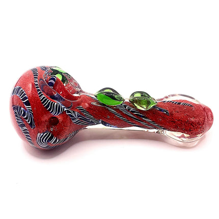 Horizontal profile of the spoon hand pipe showing the bold red body, green embellishments, and sculpted swirl design from end to end