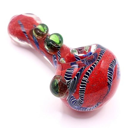 Angled product view showing the spoon pipe from the mouthpiece side with green accent beads and flowing red swirl patterns