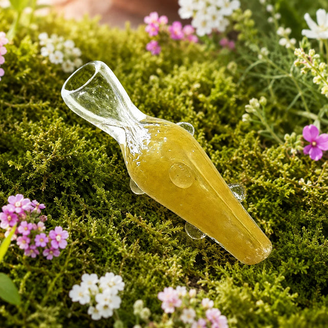 Yellow glass chillum pipe with clear mouthpiece and raised dot accents displayed on a mossy floral background