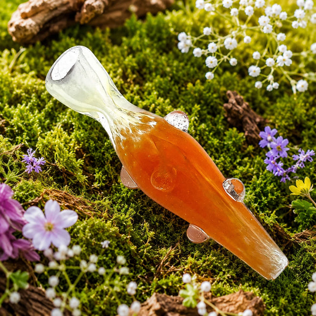 Orange glass chillum pipe with clear mouthpiece and raised dot accents displayed on a mossy floral background