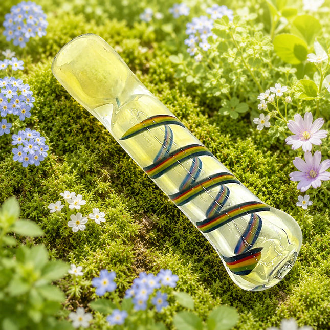 Clear 3-inch chillum styled on a bright garden background with multicolor ribbon accents wrapped around the glass body