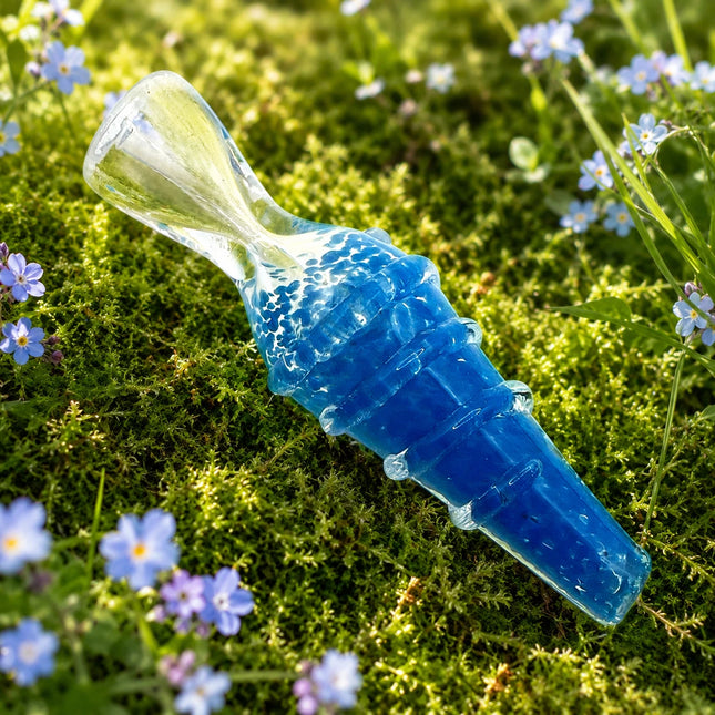 Ocean blue ribbed chillum resting among green moss and tiny purple flowers, with a pale clear mouthpiece