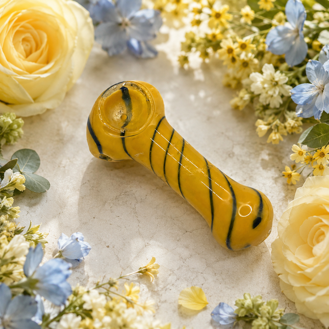 Yellow striped glass spoon hand pipe displayed on a bright floral background